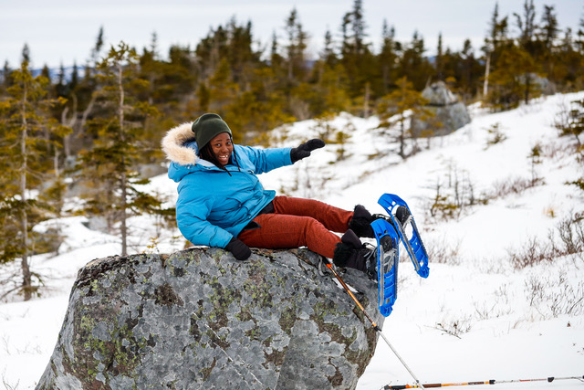 Alice enjoying a short break from snowshoeing atop a large boulder.